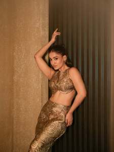 saniya-iyappan-in-high-waisted-floor-length-skirt-with-sleeveless-halter-style-crop-top-in-shimmering-metallic-gold-brocade-fabric-001