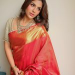 samyuktha menon in rich crimson red silk saree with contrasting off white elbow length blouse and layered necklace encrusted with green gemstones