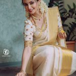 Actress sitting near Onam Pookkalam in Kasavu Saree pose