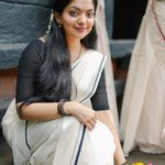 Modern minimalist sitting pose in Kerala Kasavu saree
