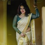 South Indian actress leaning on traditional pillar in Kerala saree