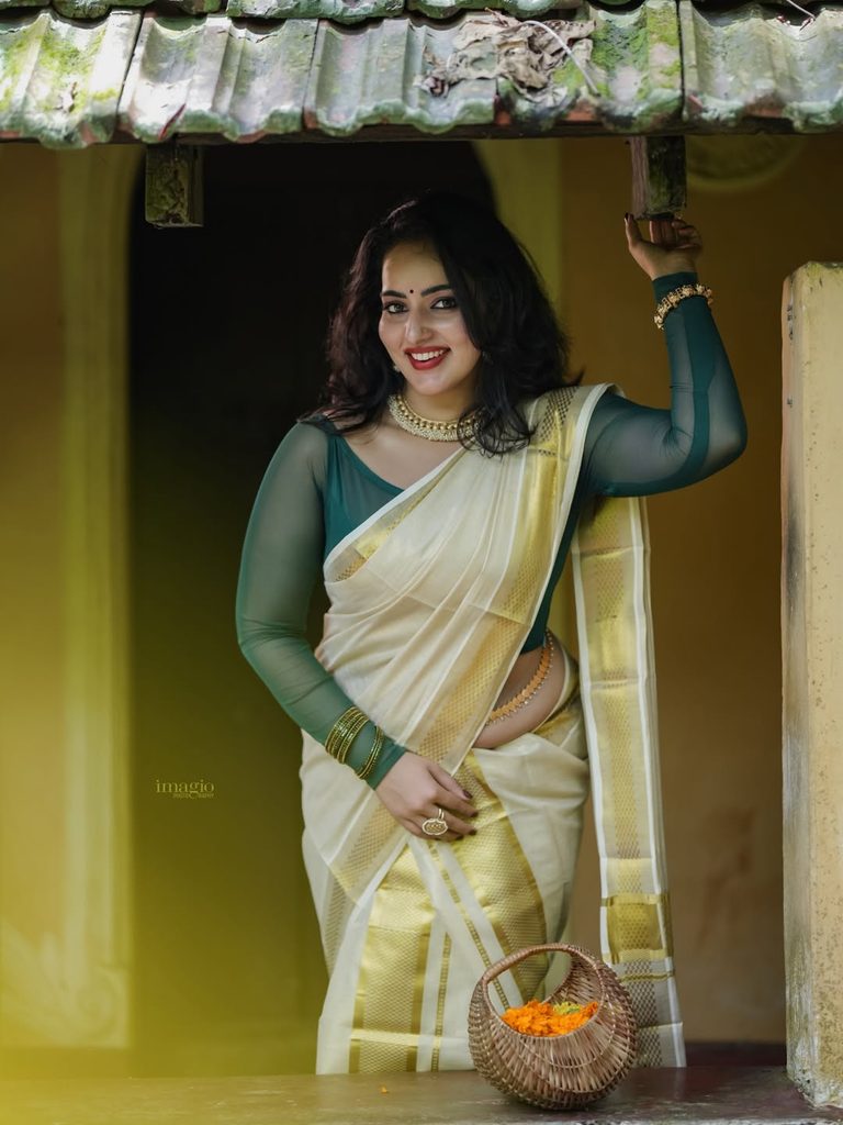 South Indian actress leaning on traditional pillar in Kerala saree