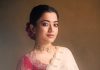 rashmika mandanna in cream colored saree with pink long sleeved blouse adorned with rich intricate gold paisley and floral embroidery design photos