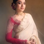 rashmika mandanna in cream colored saree with pink long sleeved blouse adorned with rich intricate gold paisley and floral embroidery design photos