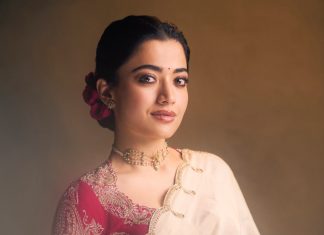 rashmika mandanna in cream colored saree with pink long sleeved blouse adorned with rich intricate gold paisley and floral embroidery design photos